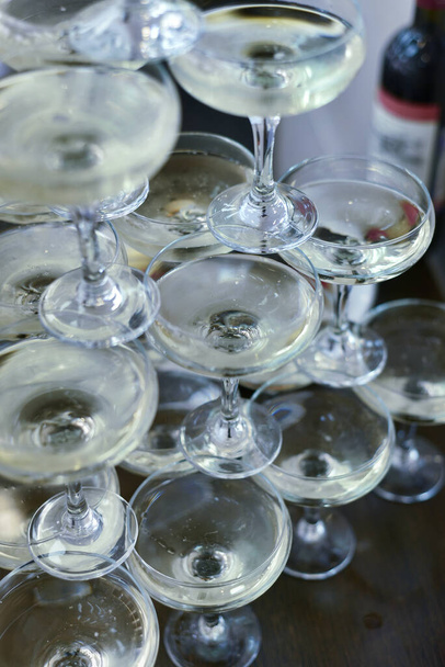 Όμορφα γυάλινα ποτήρια για κρασί και σαμπάνια, τοποθετημένα το ένα πάνω στο άλλο με τη μορφή τσουλήθρας. - Φωτογραφία, εικόνα