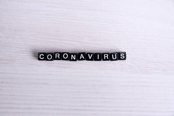 das Wort Coronavirus mit silbernen Buchstaben auf zerknüllte blaue Plastikfolie gelegt - zentrierte flache Lagekomposition mit dramatischem Licht - Foto, Bild