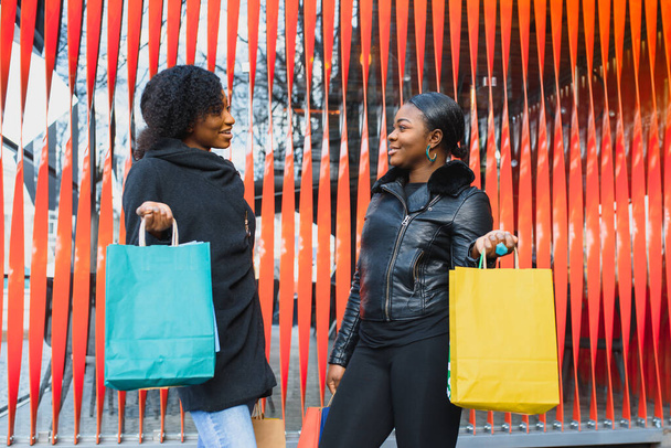 Two Smiling Black Girlfriends Shopping and Chatting - Фото, изображение