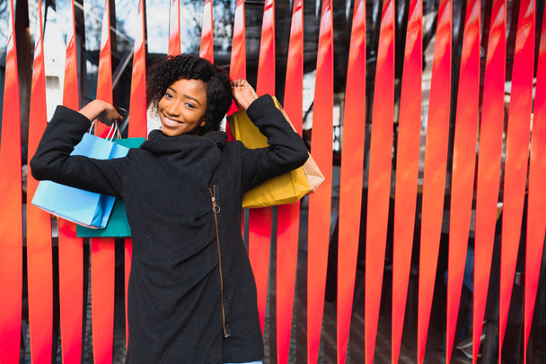 Vonzó fiatal afro-amerikai nő vásárlás - bevásárló táskák, szabadban, utcára néző, alkalmas nyaralás bevásárló témák, többek között - Fotó, kép