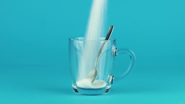 Pour cukr hrnek sklo lžička tlusté dno modrá kontrastní pozadí koncept - Záběry, video