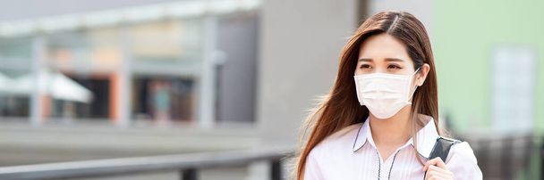Asian woman with surgical mask face protection - she commutes between home and workplace in the city - 写真・画像