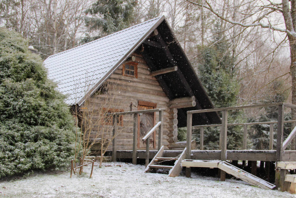 Ідилічний заміський будинок з акцентом на сніг. Дерев "яна хатина і дерев" яна палуба перед будинком.. - Фото, зображення