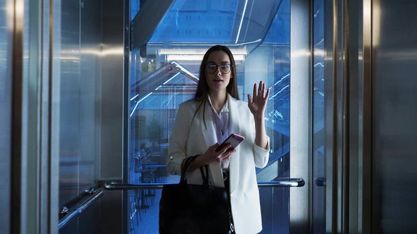 Young business lady in the Elevator in the business center, informal greeting of colleagues. - 写真・画像