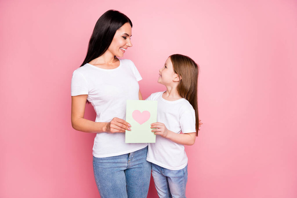 Photo of pretty young mommy little daughter hold 8 march postcard cardiac feelings hugging look eyes wear casual t-shirts jeans isolated pastel pink color background - Foto, immagini