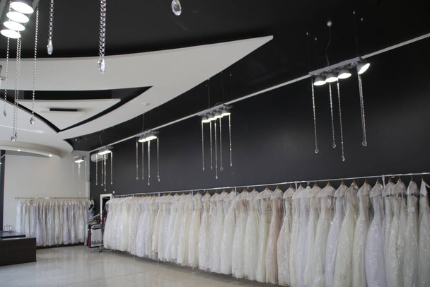 dużo sukienek ślubnych na długim blacie w sklepie - Zdjęcie, obraz