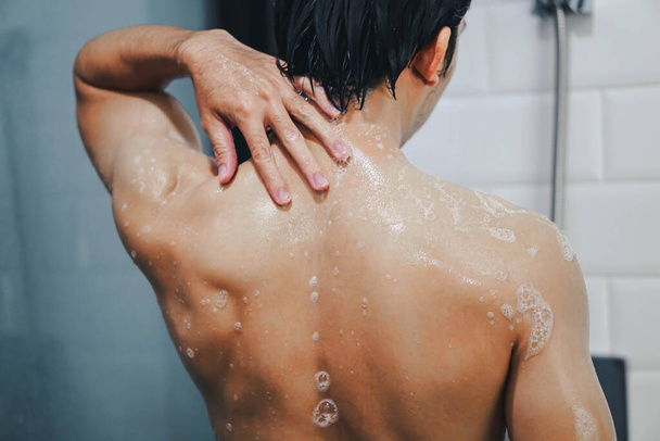Yakın plan yakışıklı Asyalı adam banyoda duş alıyor, klasik ton, seçici odaklanma. - Fotoğraf, Görsel