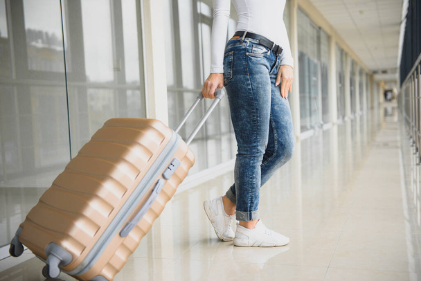 A woman with hand luggage walking in airport terminal - Фото, зображення