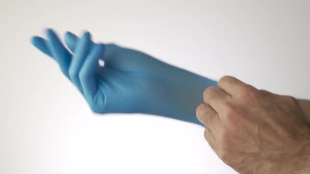 Putting on blue gloves on a white background - Felvétel, videó