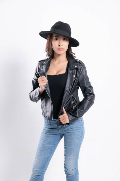 Portré ázsiai fiatal nő fekete bőrdzsekiben visel fekete kalap divat stúdió lövés elszigetelt fehér háttér. - Fotó, kép