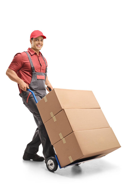 Male worker pushing a hand truck loaded with boxes isolated on white background - Photo, Image