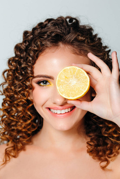 Portrait of young beautiful smiling women with curly hair. Funny girl with wavy hairstyle and bright make up on in a studio. Summer calendar girl. - 写真・画像