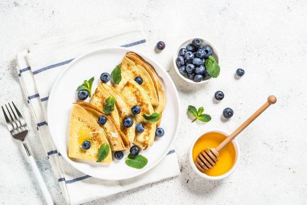 Crepes with blueberries at white table. - Фото, зображення