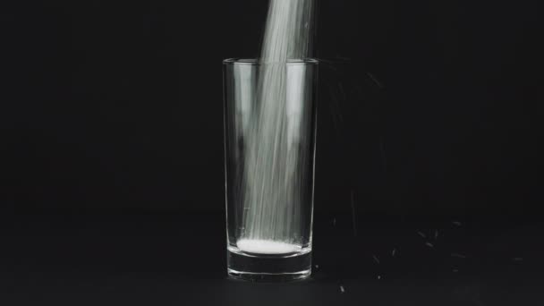 Versare lo zucchero highball vetro fondo spesso sfondo nero a contrasto. Concetto
 - Filmati, video