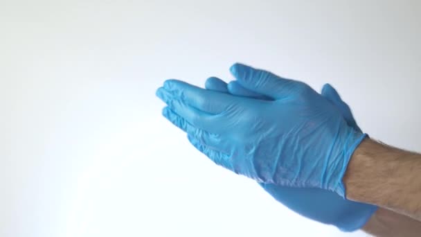 Medische handen met blauwe handschoenen klapperend op witte achtergrond - Video