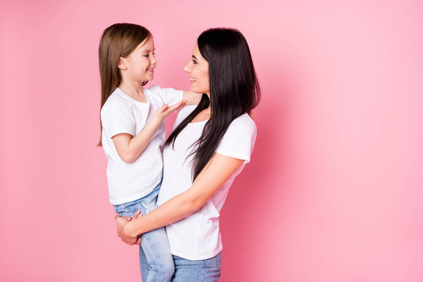 Portrait of two nice attractive lovely cute sweet careful cheerful cheery friendly sisters mom carrying daughter speaking contact growing up isolated over pink pastel color background - 写真・画像