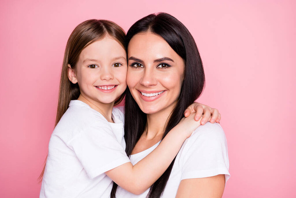 Closeup photo of beautiful young mother hold arms little daughter hugging best friends sincere cardiac feelings wear casual white t-shirts isolated pastel pink color background - Foto, Bild