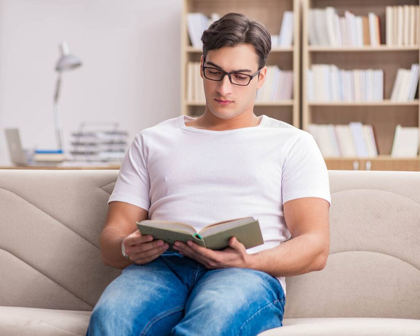 Mężczyzna czytanie książki siedzi w kanapie - Zdjęcie, obraz