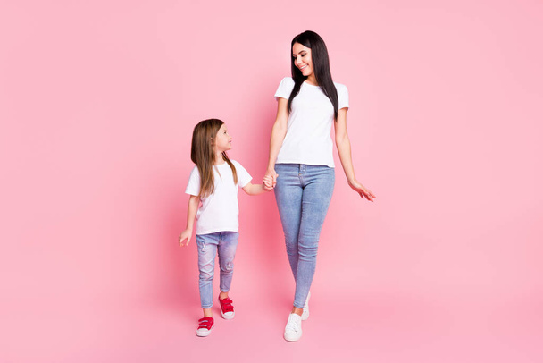 Full length body size view of two nice attractive lovely pretty cheerful cheery careful friendly best sisters walking enjoying holding hands isolated over pink pastel color background - Fotografie, Obrázek