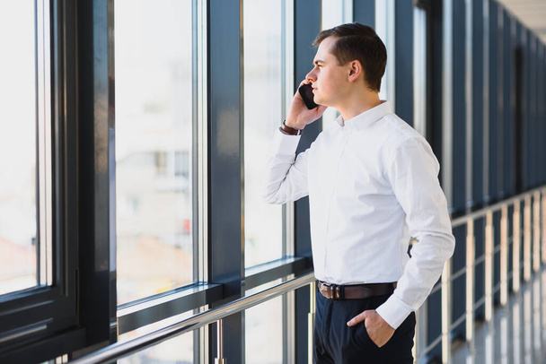 Handsome young businessman near window in office - Photo, Image