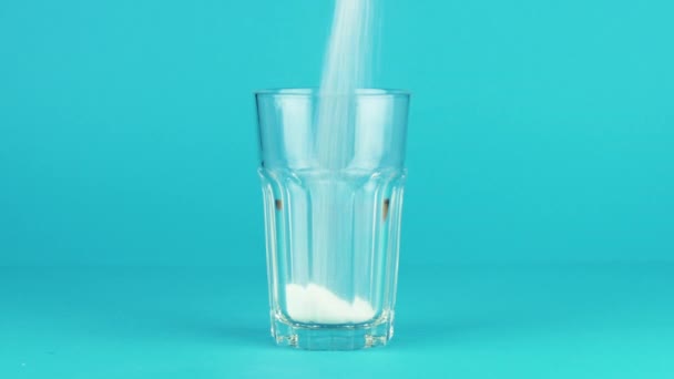 Versare zucchero collins vetro fondo spesso sfondo blu a contrasto. Concetto
 - Filmati, video