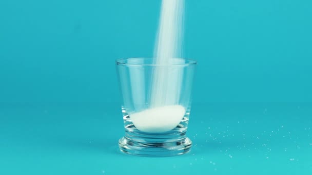 Giet suiker glas schot dikke bodem blauw contrasterende achtergrond. Concept - Video