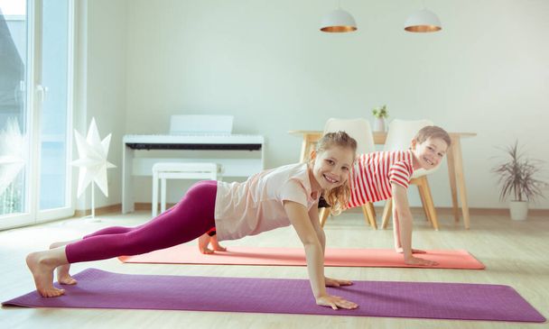 Happy siblings children making yoga at home dueing coronavirus quarantine - Foto, immagini