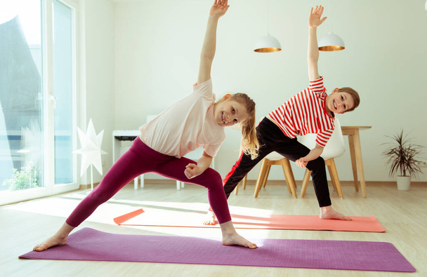 Happy siblings children making yoga at home dueing coronavirus quarantine - Fotoğraf, Görsel