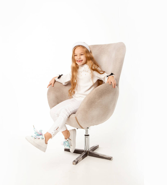 girl with long hair, dressed in white clothes, sits in a chair - Photo, Image