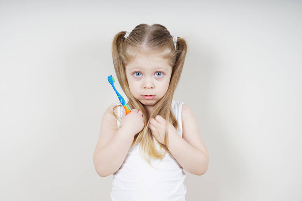 A little girl of European appearance brushes her teeth on a light background. The concept of healthy teeth. Dentistry - Foto, immagini