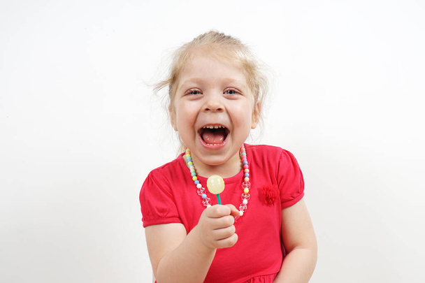 Cheerful little blonde girl in a pink dress for advertising. Lollipop in the hands. - Foto, Imagem