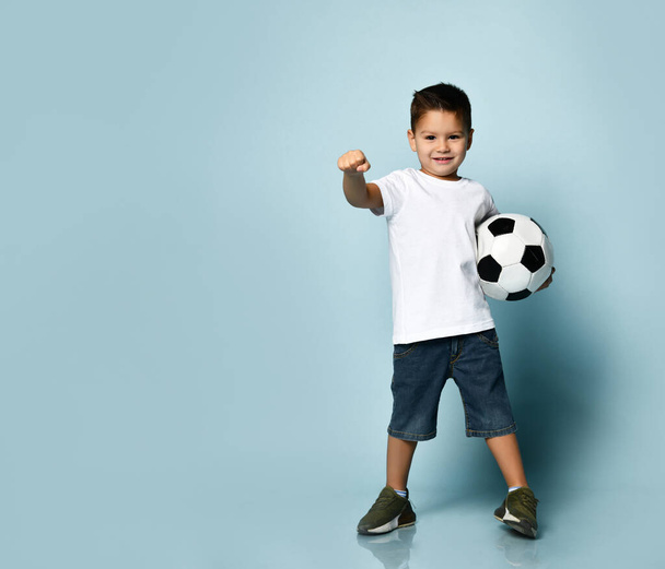 Cute boy playing football, happy child, young male teen goalkeeper enjoying sport game, holding ball, isolated portrait of a preteen smiling and having fun - Foto, afbeelding