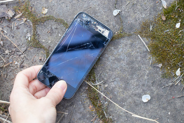 Ukraine, Dnipro - April 03, 2020. An old broken iPhone 4 lies on a stone.Ukraine, Dnipro - April 03, 2020. An old broken iPhone 4 lies on a stone close-up. - Photo, Image