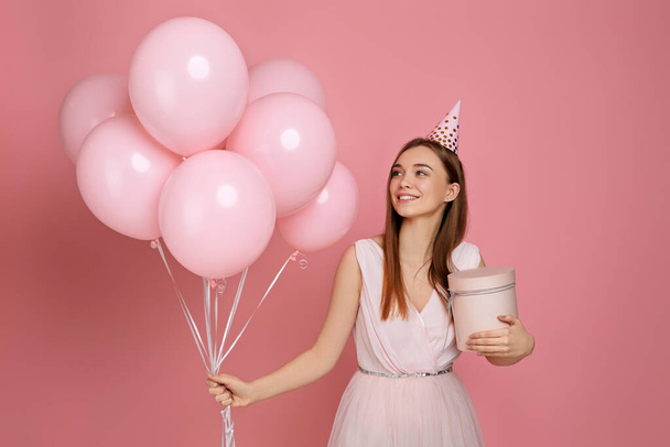 woman in birthday hat celebrating with pastel pink air balloons - Φωτογραφία, εικόνα