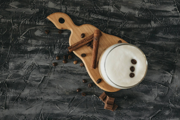 cappuccino com pau de canela e grãos de café e chocolate na mesa
 - Foto, Imagem