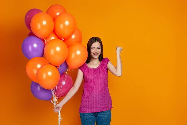 girl with bright colorful air balloons raises clenched fists - Photo, Image