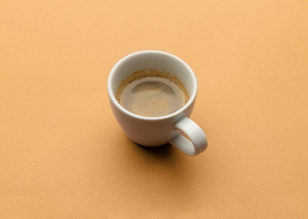 Espresso coffee in white cup on beige table. Pop art minimal flat lay creative composition. Morning breakfast background - Photo, Image