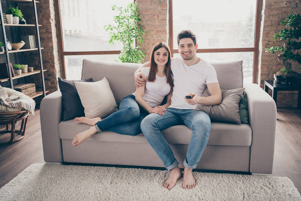 Portrait of her she his he nice attractive lovely cheerful cheery couple sitting on divan having fun watching TV at modern industrial loft style brick interior living-room flat indoors - Foto, Imagen
