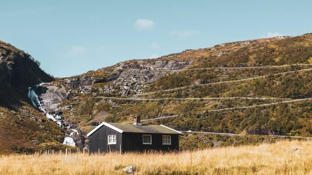 Norweski tradycyjny czarny dom na wąż górskiej drogi na wzgórzu odległość kolor stopniowany widok. Jesienny dysk Skandynawia Myrkdalsvegen Serpentinveg, Sendefossen - Zdjęcie, obraz
