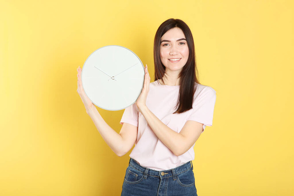 Girl holds a mechanical clock on a colored background - Foto, Imagem