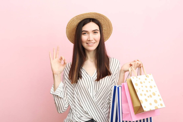 Krásná mladá dívka s papírovými taškami pro nakupování na barevném pozadí - Fotografie, Obrázek