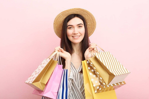 Красивая молодая девушка с бумажными пакетами для покупок на цветном фоне
 - Фото, изображение