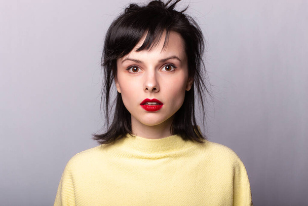 girl with red lipstick on the lips in a yellow sweater - Фото, зображення