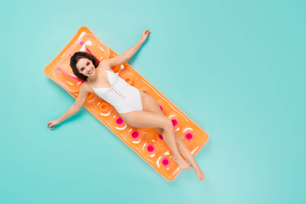 Top above high angle full size photo of positive girl enjoy recreation resort swim lay inflatable orange mattress ocean wear style trendy body suit isolated over turquoise color background - Fotó, kép
