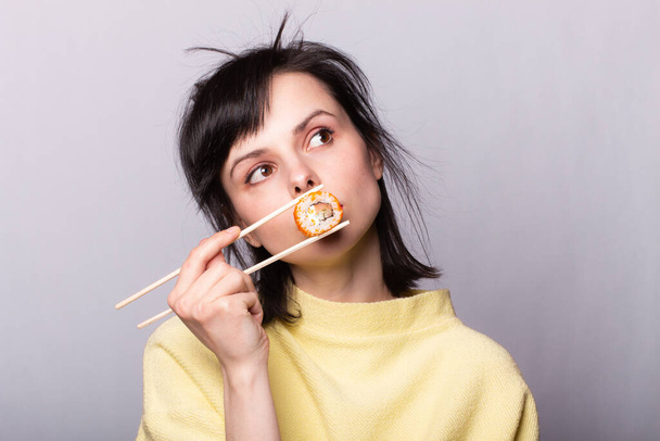 Woman with food in her hands. Sushi on sticks - Foto, afbeelding