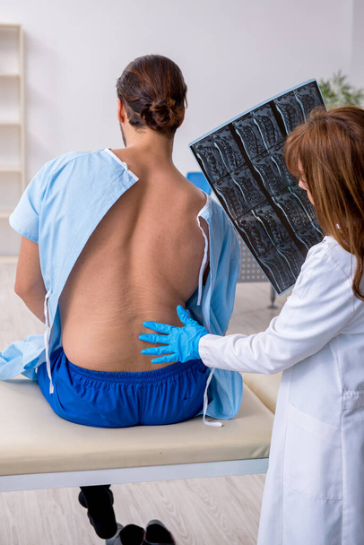 Young back injured man visiting female doctor chiropractor - Photo, Image