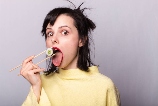 Woman eating sushi with chopsticks, rolls, asia, japan - Foto, afbeelding