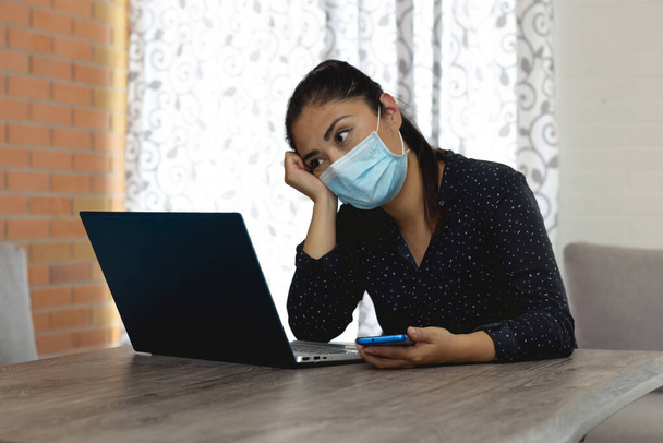 Женщина в маске работает дома на случай болезни Ковида-19. Министерство внутренних дел. Чрезвычайная ситуация
. - Фото, изображение