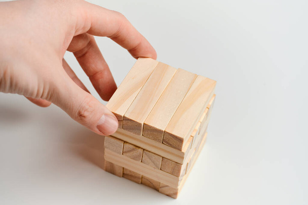 The concept of creating branding. Hand holds wooden blocks on a white background. Close up. - Photo, Image