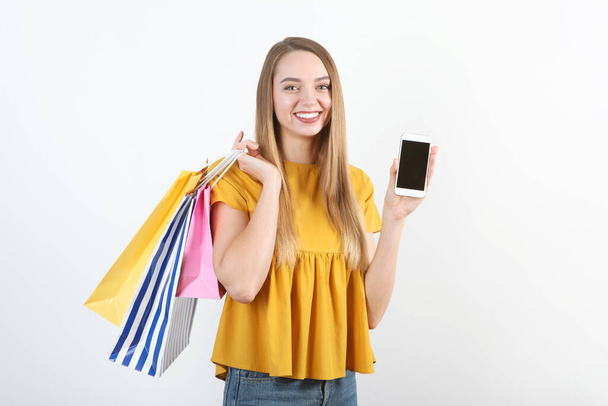 Belle jeune fille avec des sacs en papier pour faire du shopping sur un fond coloré
 - Photo, image